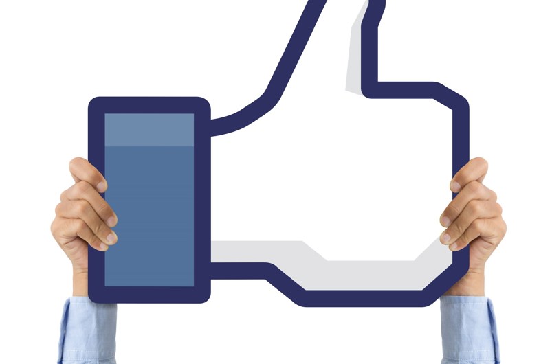 Strakte arme, der holder et like-symbol fra Facebook