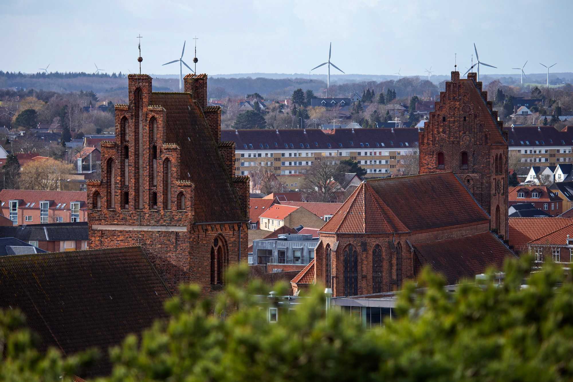 Dronefoto af Næstved Kirkes tårne og vindmøller i baggrunden