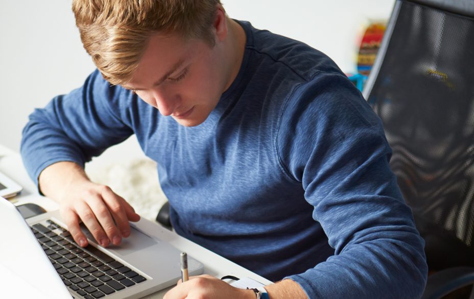 På billedet ses en mand ved en pc. Han noterer i en blok