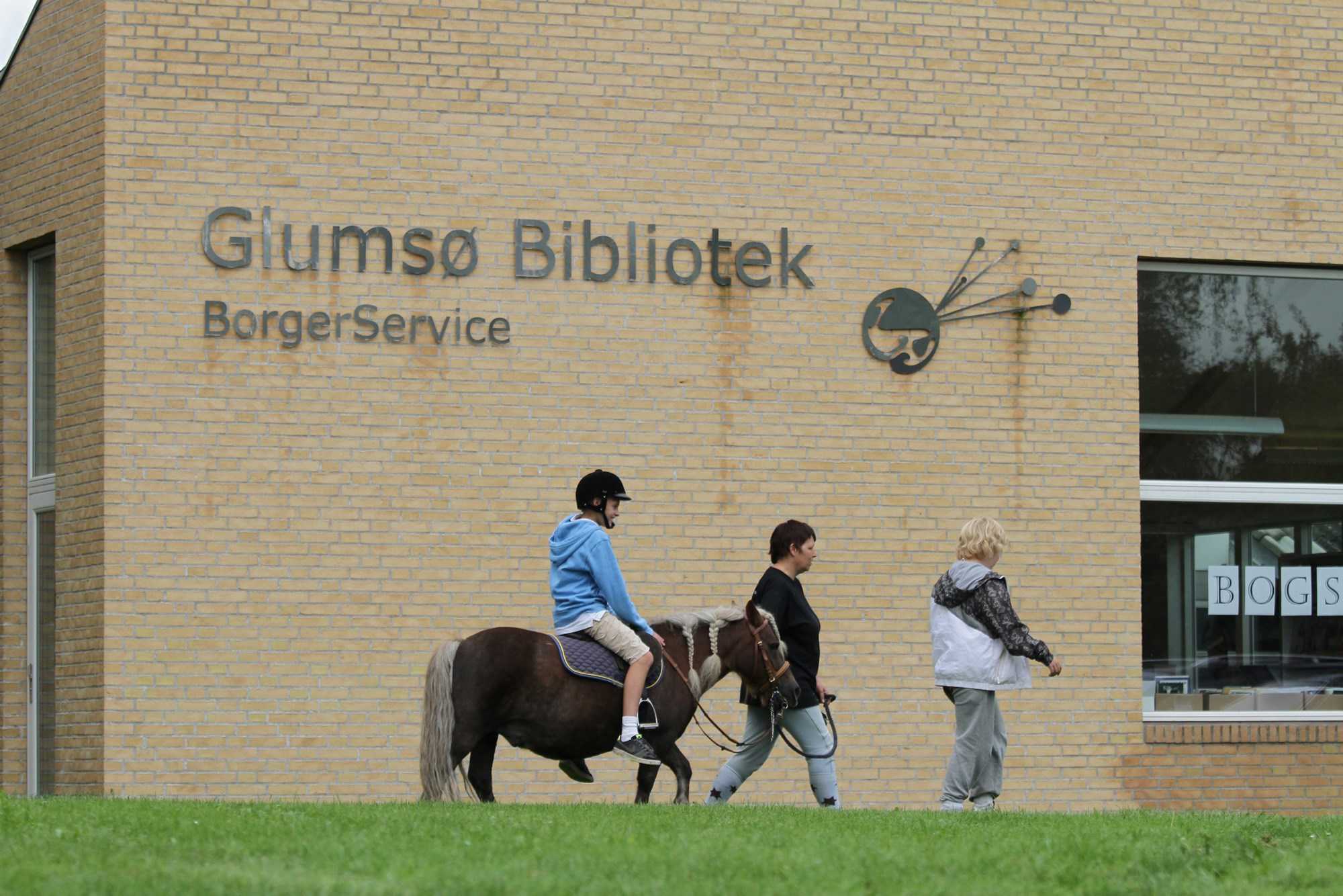 Barn trækkes på pony foran Glumsø Bibliotek Og Borgerservice