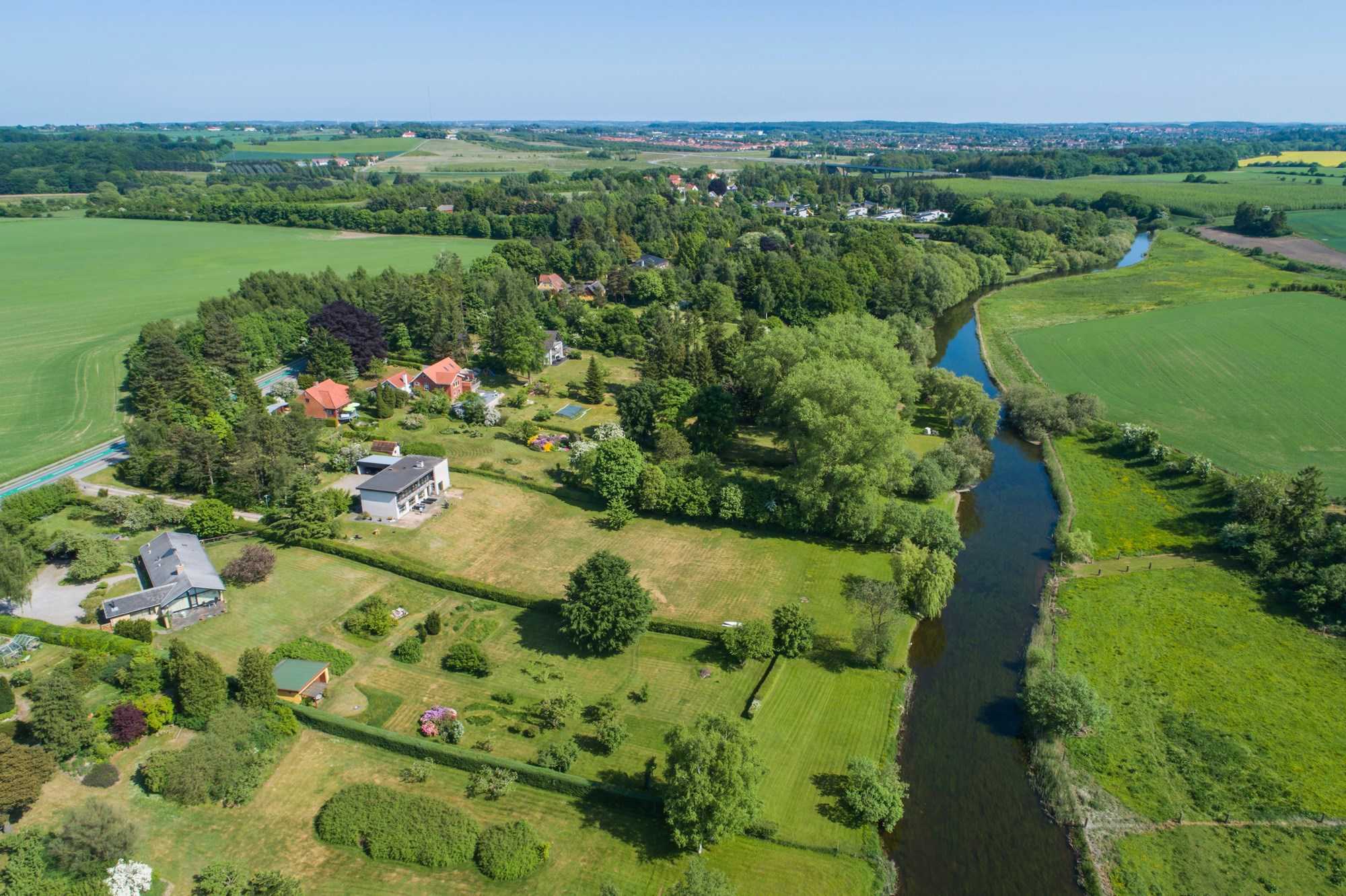 Dronefoto over Fensmark med Susåen der løber forbi 