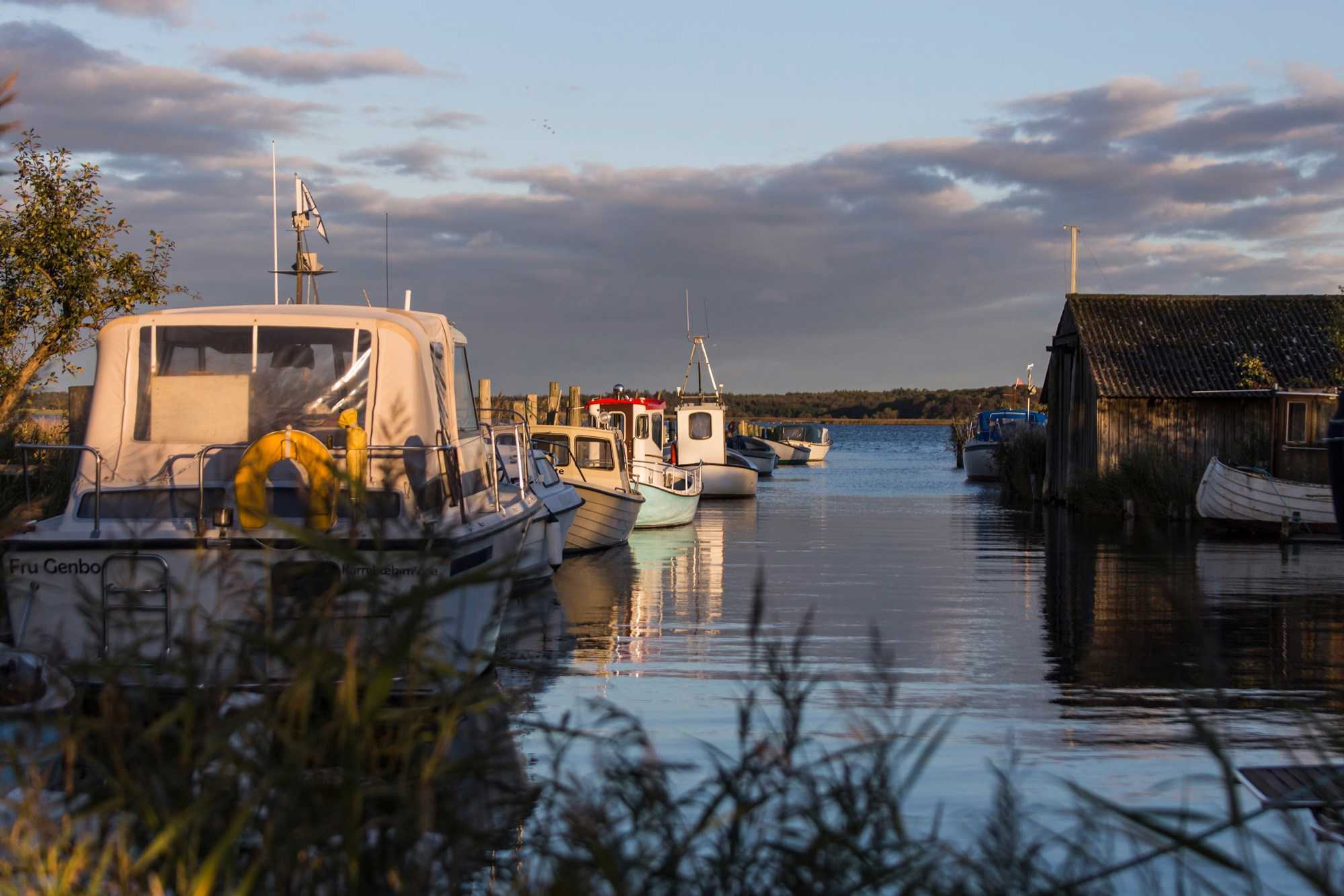 Både står forankret med solnedgang i baggrunden ved Karrebæksminde