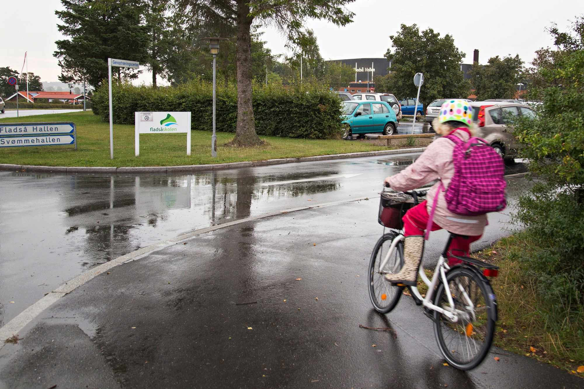 Pige på cykel drejer ad vejen mod Fladså skole og Hallen