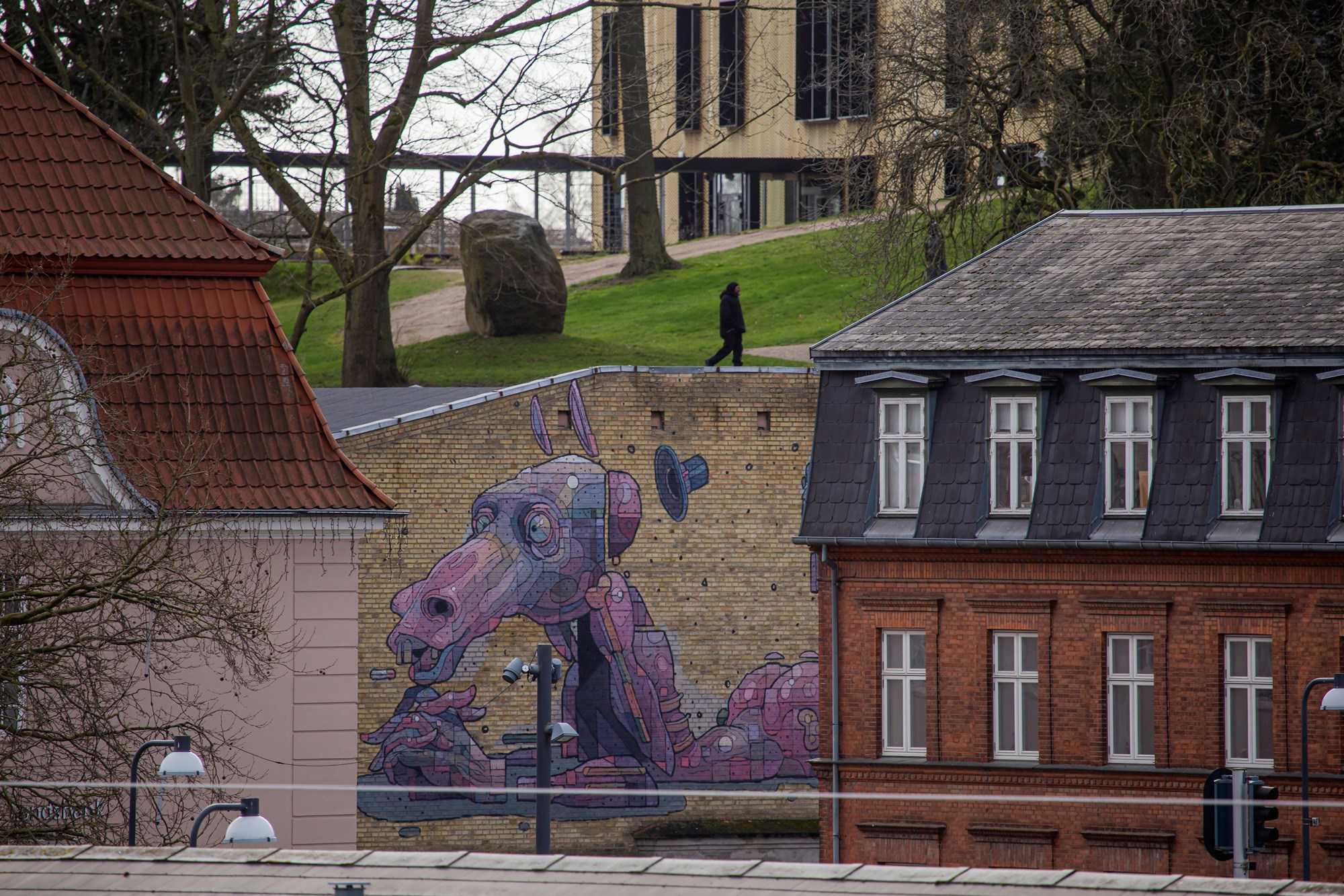 Graffiti af en lilla drage på gavlen foran Biblioteket i Næstved Bymidte