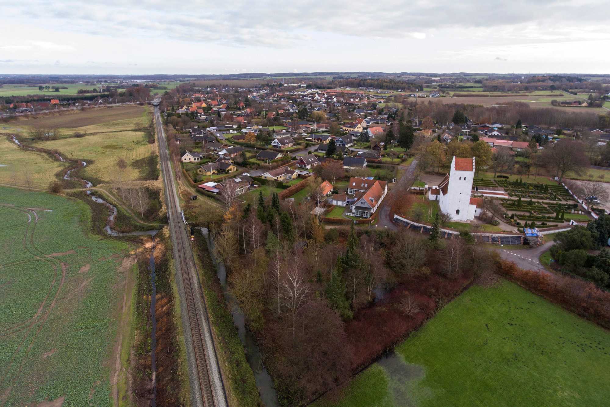 Holme Olstrup dronebillede af togskinner og kirken bagved