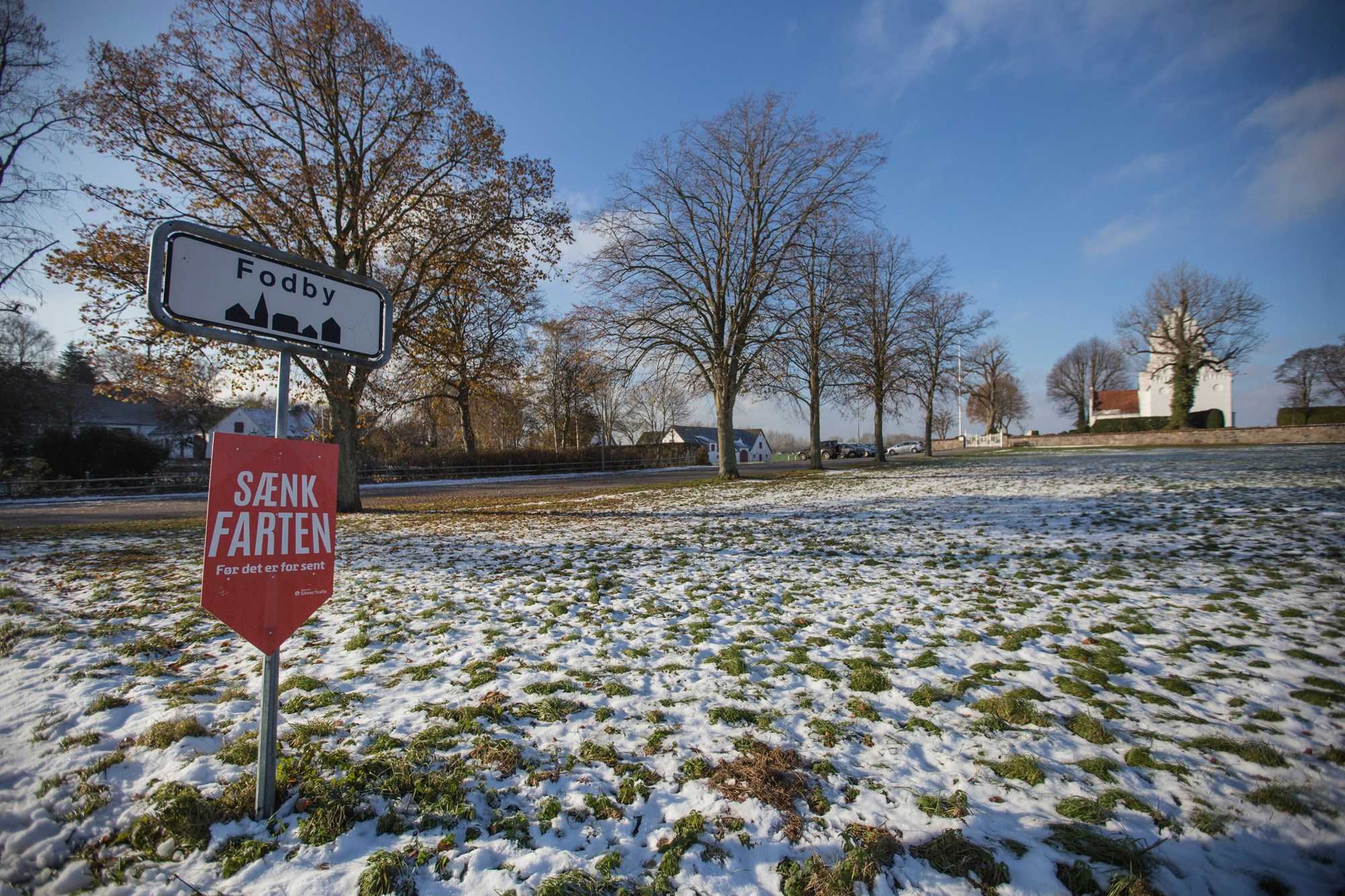 Fodby byskilt på snedækket landskab foran Fodby kirke