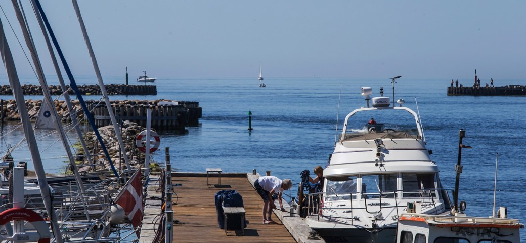 En kvinde står på bådebroen og tager imod en båd der lægger til i Karrebæksminde