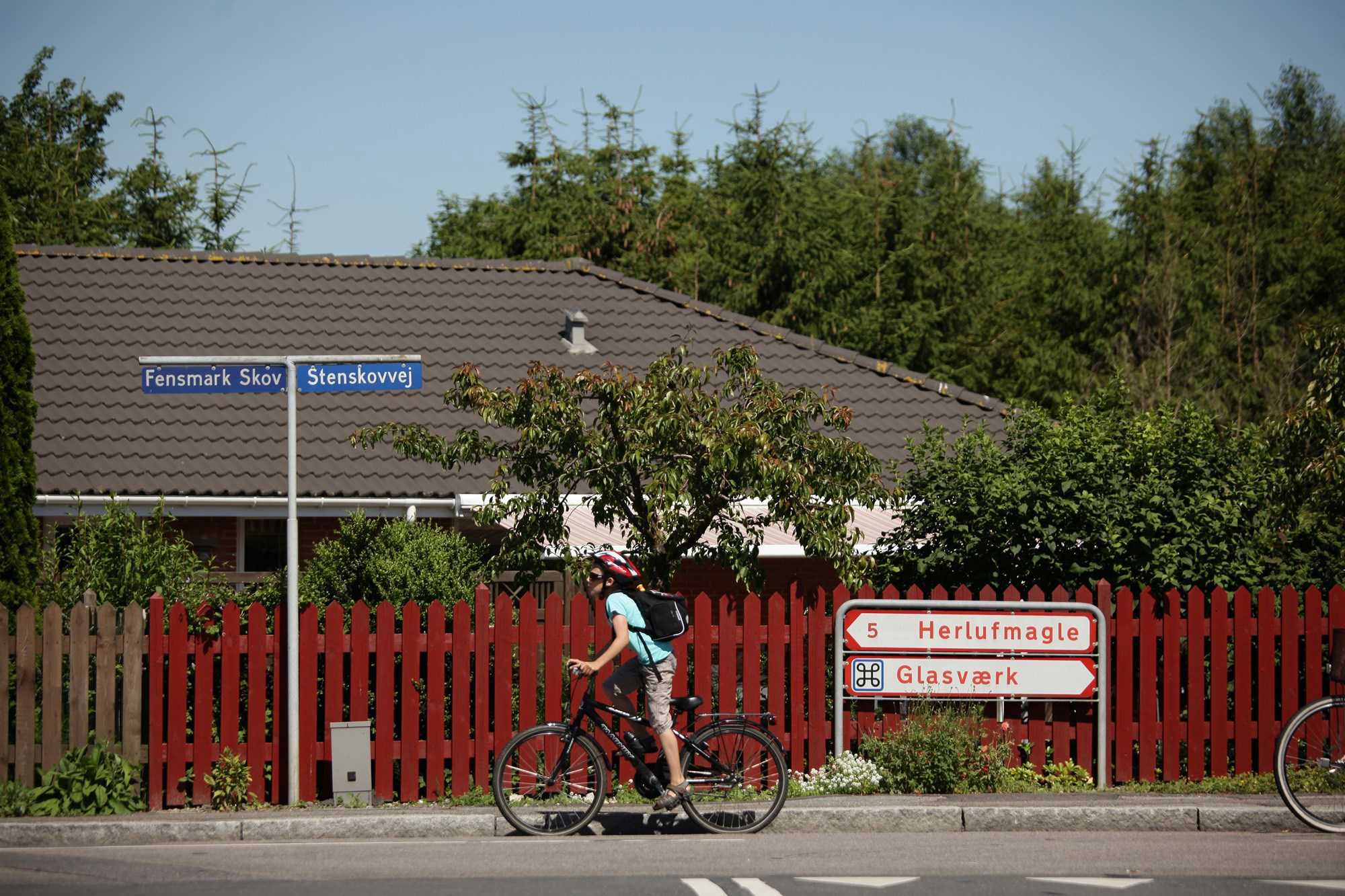 Et barn på cykel foran byskilte i Fensmark