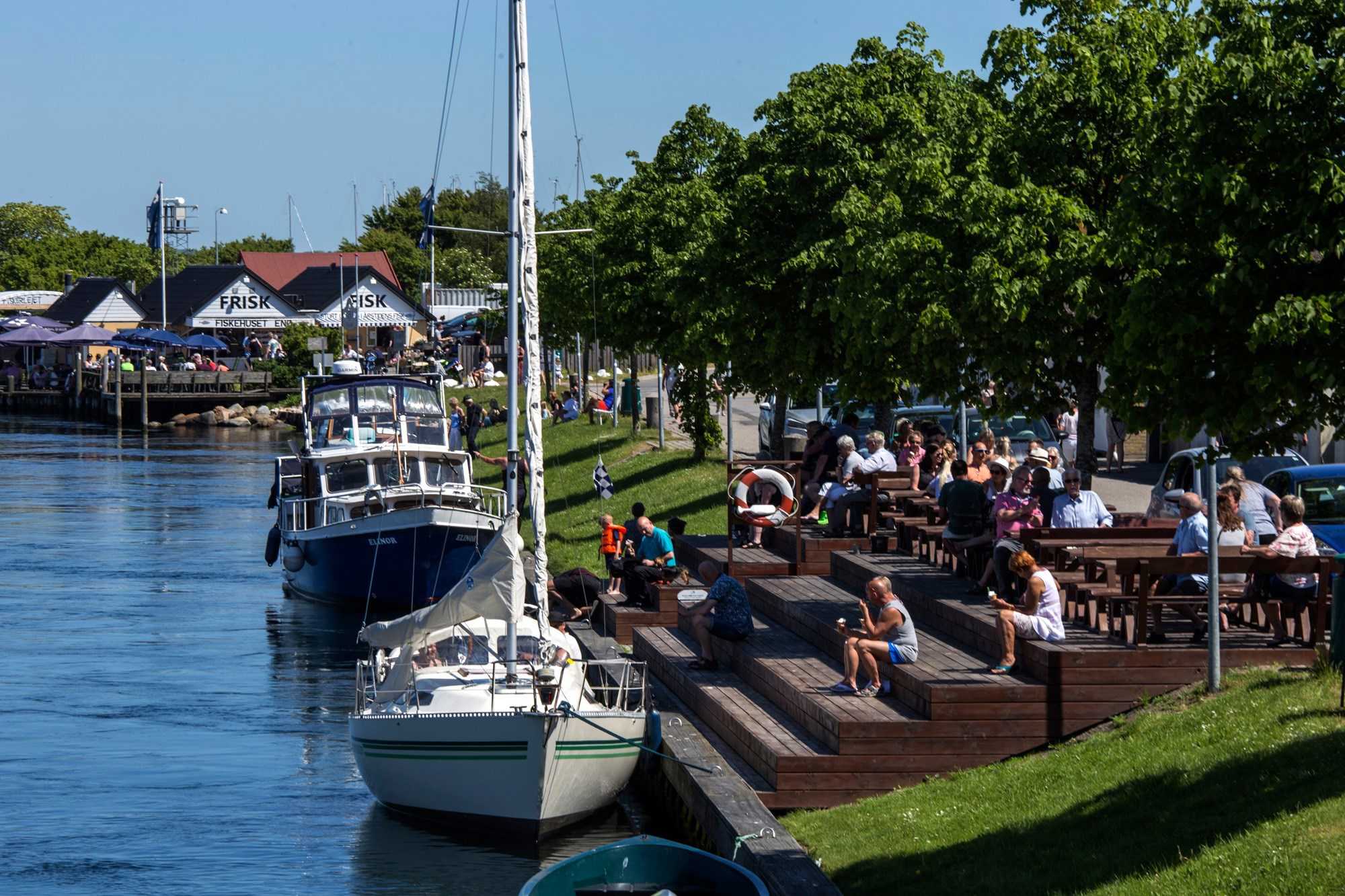 Mennesker sidder ved trappe foran Fiskebutik i Karrebæksminde